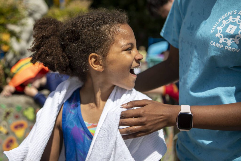 Joliviya “Jo Jo” Plakio, 7, smiles while drying off after playing in the water park during Camp Prov at Forest Park in Everett, Washington on Wednesday, July 24, 2024. (Annie Barker / The Herald)
