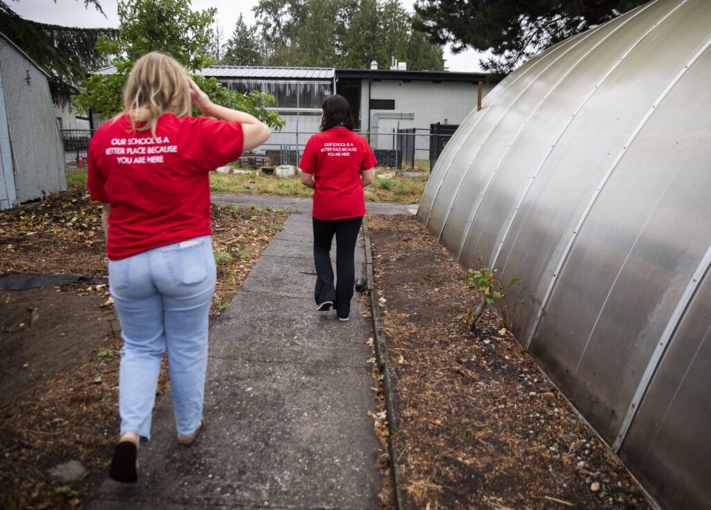 Claire Luvera, left, and Kayla Carter walks down a concrete path that they discovered only after clearing away blackberries on Monday in Marysville. (Olivia Vanni / The Herald)
