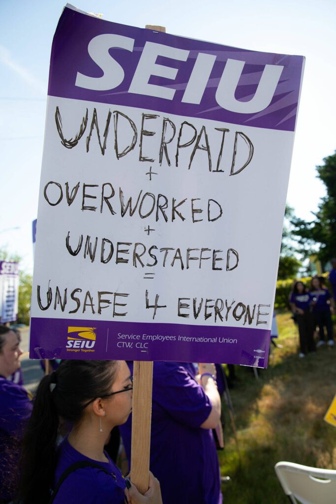 A Compass Health worker holds a picket sign during a rally after picketing in front of the Compass Evaluation and Treatment building on Thursday, Aug. 1, 2024, in Mukilteo, Washington. (Ryan Berry / The Herald)
