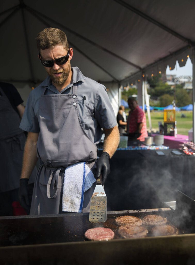 Brandon Carow from The Victor Tavern cooks up burger at Taste Edmonds on Friday in Edmonds. (Olivia Vanni / The Herald)

