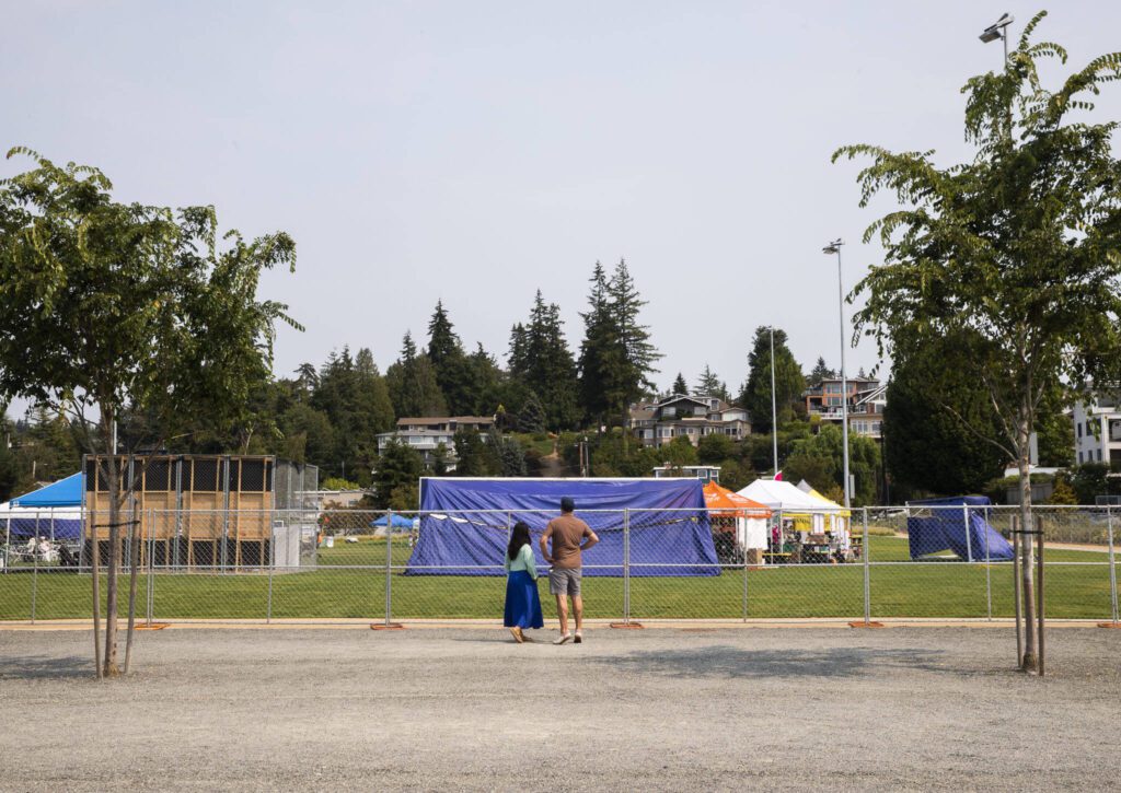 People look over the fence before the opening of Taste Edmonds on Friday in Edmonds. (Olivia Vanni / The Herald)
