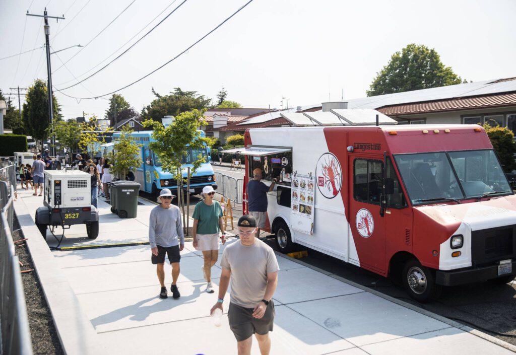 People walks past a selection of food trucks at Taste Edmonds on Friday in Edmonds. (Olivia Vanni / The Herald)

