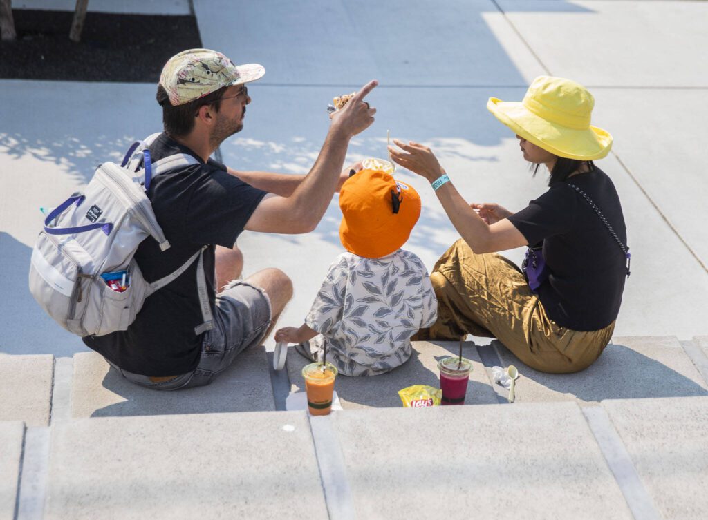 Kyle Travess, left, Oakley, 2, and Sophia Jiang share food at Taste Edmonds on Friday in Edmonds. (Olivia Vanni / The Herald)
