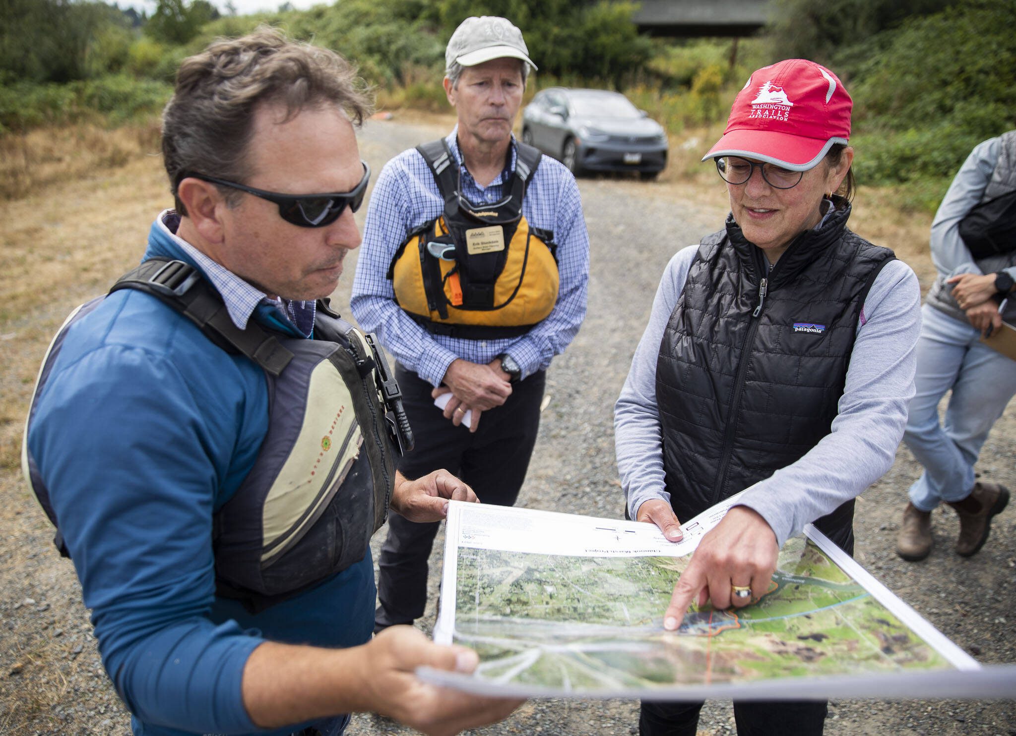 U.S. Rep. Suzan DelBene, right, goes over a Chinook Marsh project map with Snohomish County Surface Water Management’s Michael Rustay, left, and Erik Stockdale, center, at the project site on Tuesday in Snohomish. (Olivia Vanni / The Herald)