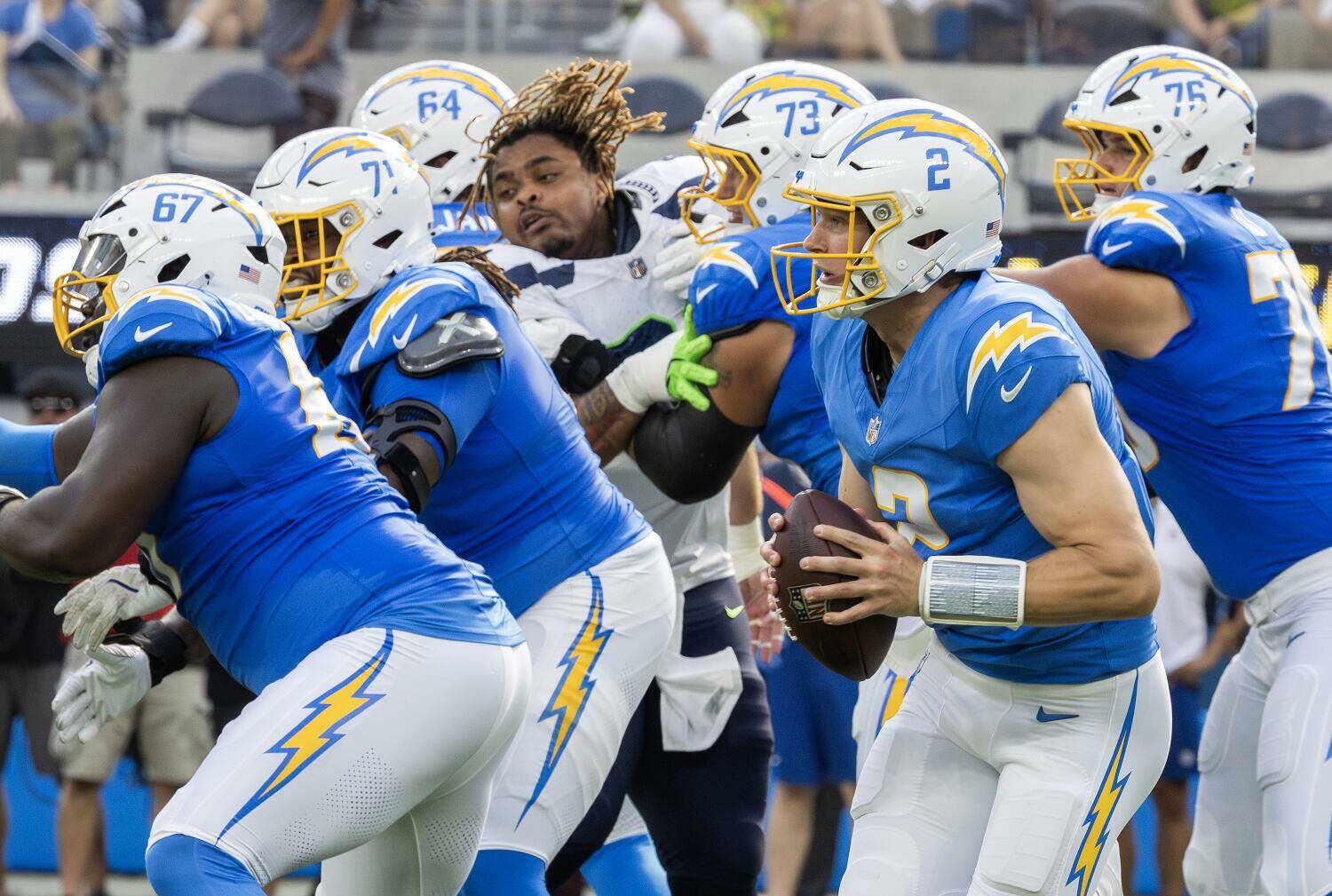 Myung J. Chun / Los Angeles Times
Los Angeles Chargers quarterback Easton Stick (#2) gets chased out of the pocket as Seattle Seahawks defensive tackle Byron Murphy loses his helmet during second quarter preseason play at SoFi Stadium in Inglewood, CA on Saturday.