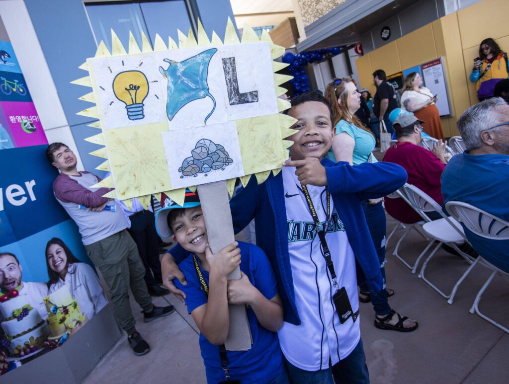 Luqman Allsot, 8, left, and Abrahin Allsot, 11, right holds a sign they made celebrating the light rail during the Lynnwood 1 Line extension opening celebrations on Friday, Aug. 30, 2024 in Lynnwood, Washington. (Olivia Vanni / The Herald)
