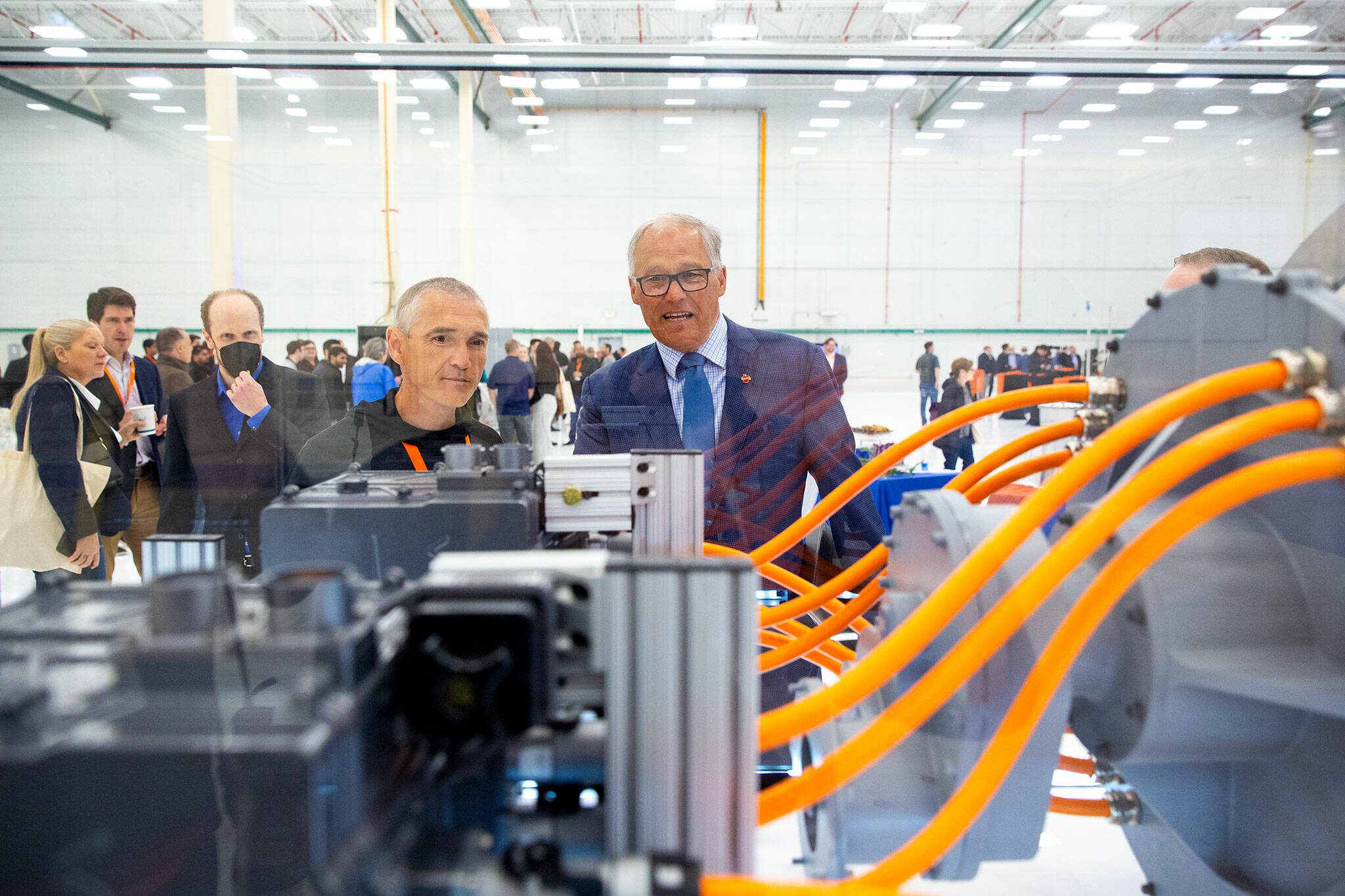ZeroAvia founder and CEO Val Mifthakof, left, shows Gov. Jay Inslee a hydrogen-powered motor during an event at ZeroAvia’s new Everett facility in April near Paine Field in Everett. (Ryan Berry / The Herald)