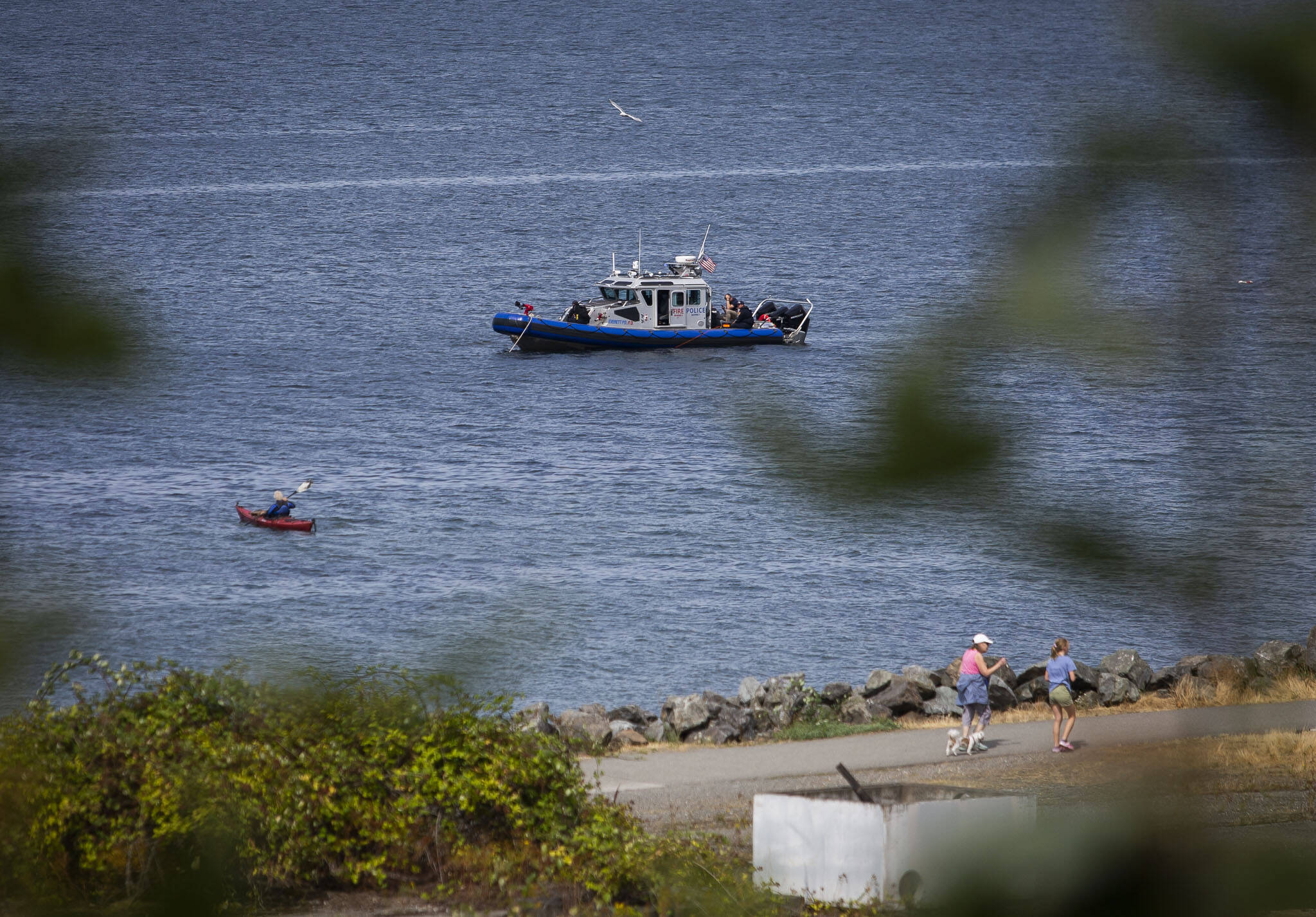 An Everett Police boat is visible from Edgewater Beach on Monday as the search continues for a kayaker that went missing after a storm on Sunday near Mukilteo. (Olivia Vanni / The Herald)