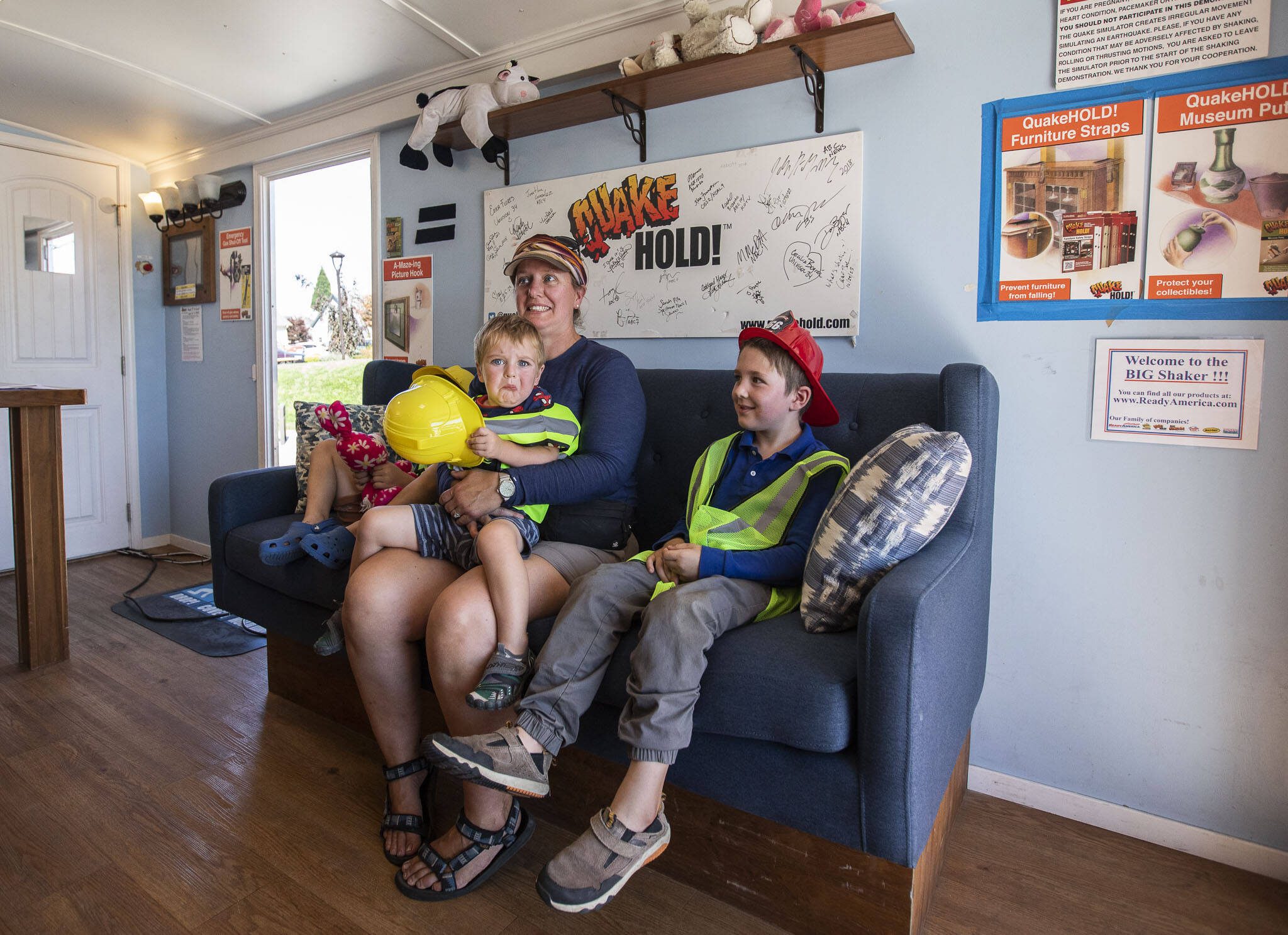 Jill Diner, center, holds her son Sam, 2, while he reacts to the shaking of the Big Shaker, the world’s largest mobile earthquake simulator, with his siblings on Thursday in Marysville. (Olivia Vanni / The Herald)