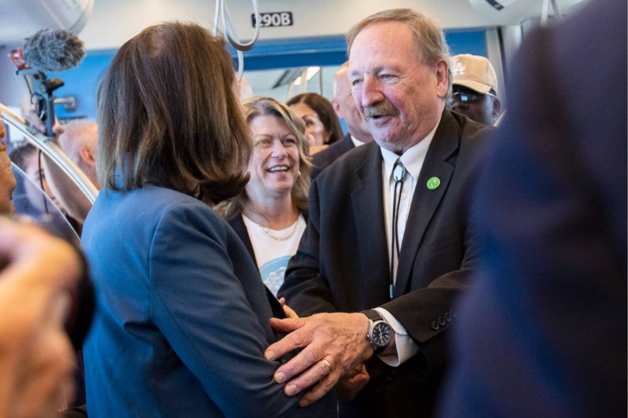 Snohomish County Executive Dave Somers and Senator Maria Cantrell shake hands as they board the 12:30 pm train during the Lynnwood 1 Line extension opening celebrations on Friday in Lynnwood. (Olivia Vanni / The Herald)