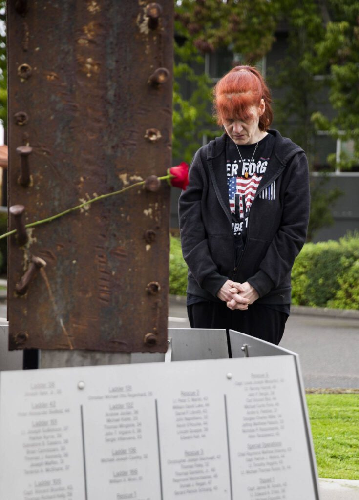 Natasha Atsatt, wearing a ‘Never Forget’ shirt, takes a moment to read the names of those lost listed at the base of the 9/11 memorial built around a 1-ton beam recovered from the collapsed World Trade Center on Wednesday, Sept. 11, 2024, in Edmonds, Washington. (Olivia Vanni / The Herald)
