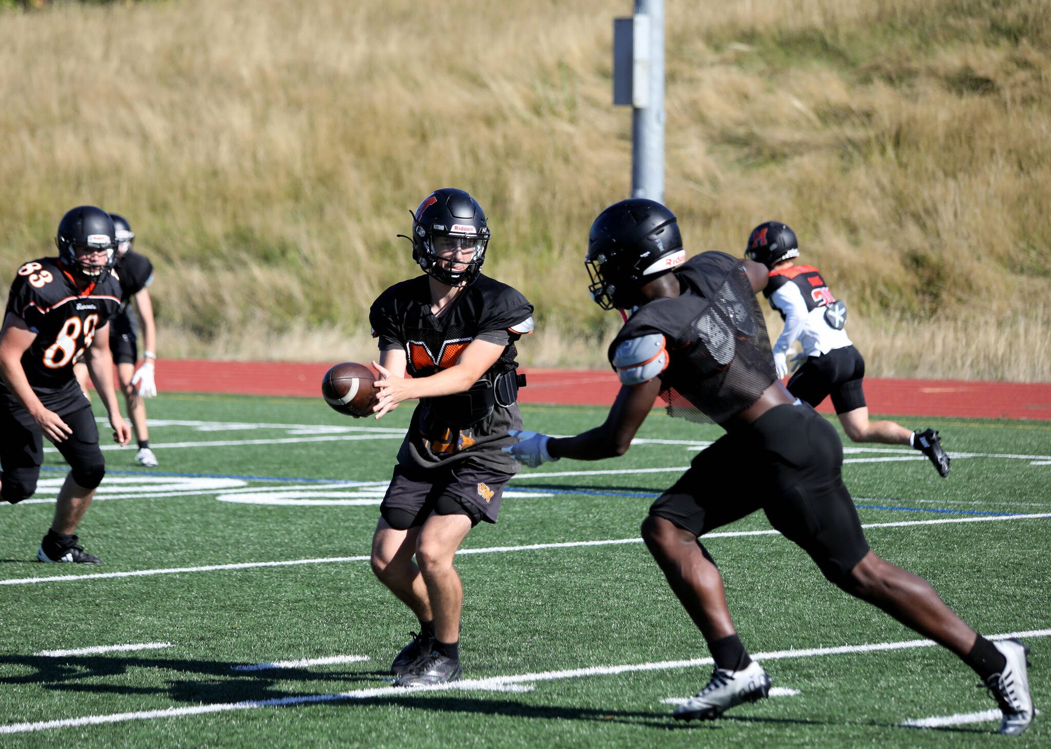 Senior quarterback Logan Manson hands off the football to senior running back Carl Watson III during a drill at the Monroe High School football practice in Monroe, Washington on Aug. 29, 2024. (Taras McCurdie / The Herald)