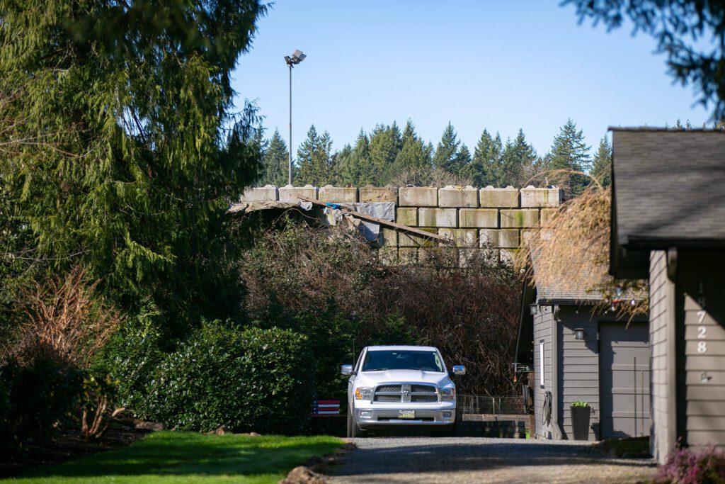 A cement block wall holds back refuse at United Recycling and Containers behind a home. Years ago, the homes on 109th Ave SE overlooked a 150-foot drop into an old gravel pit. (Ryan Berry / The Herald)
