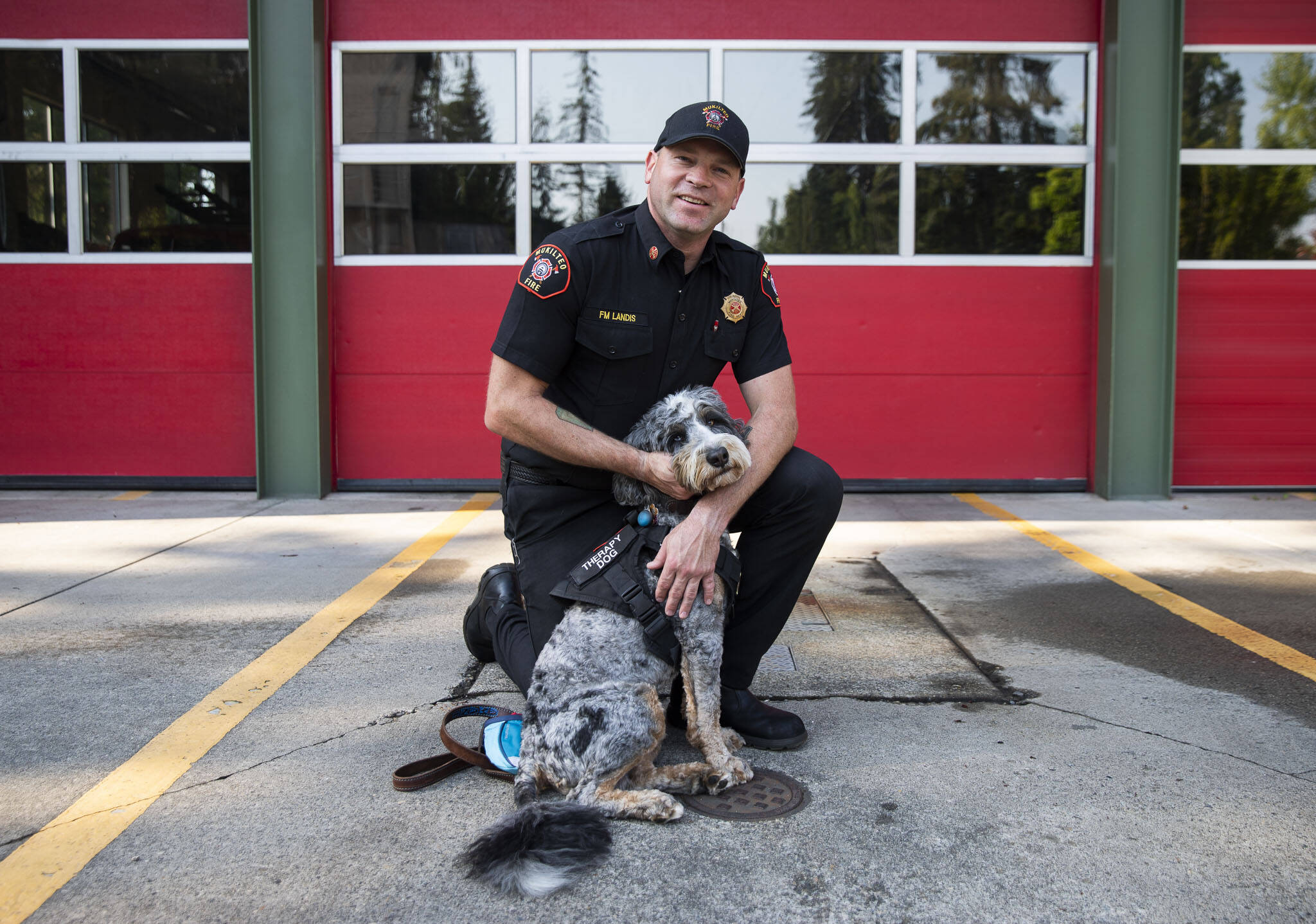 Fire Marshal Derek Landis with his bernedoodle therapy dog Amani, 1, at the Mukilteo Fire Department on Thursday, Sept. 5, 2024 in Mukilteo, Washington. (Olivia Vanni / The Herald)