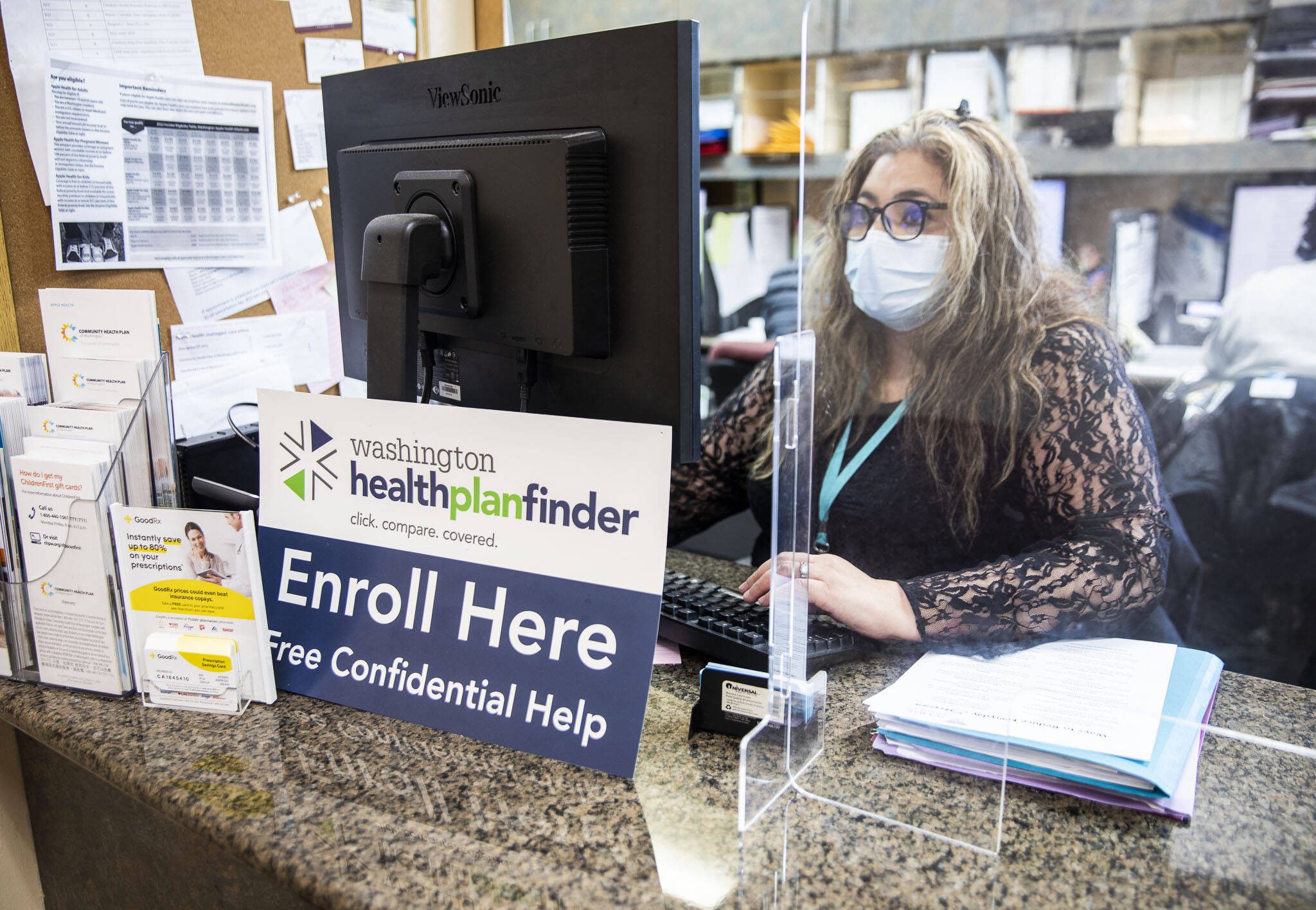 Annaberies Colmena, a patient navigator, sits behind an open enrollment flyer at Sea Mar in 2022 in Everett. (Olivia Vanni / The Herald)