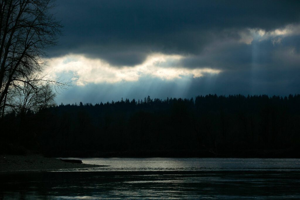 Streaks of light shine through the clouds over the Snohomish River on Wednesday, Dec. 14, 2022, at Bob Heirman Wildlife Park at Thomas’ Eddy in Snohomish, Washington. (Ryan Berry / The Herald)
