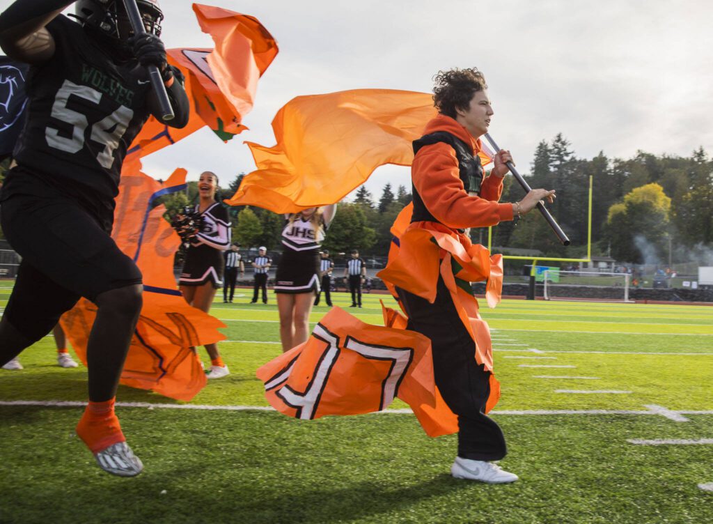 Will Turpin holds an orange flag and rips through a poster with his team during their “orange out” game for leukemia awareness on Friday, Sept. 20, 2024 in Everett, Washington. (Olivia Vanni / The Herald)
