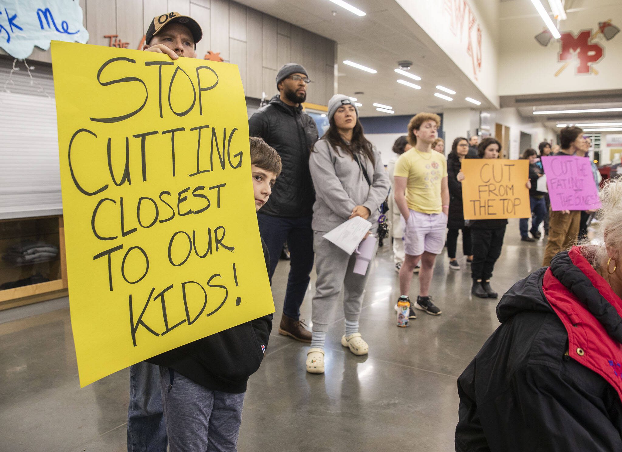 Grayson Huff, left, a 4th grader at Pinewood Elementary, peeks around his sign during the Marysville School District budget presentation on Tuesday, Nov. 28, 2023 in Marysville, Washington. (Olivia Vanni / The Herald)