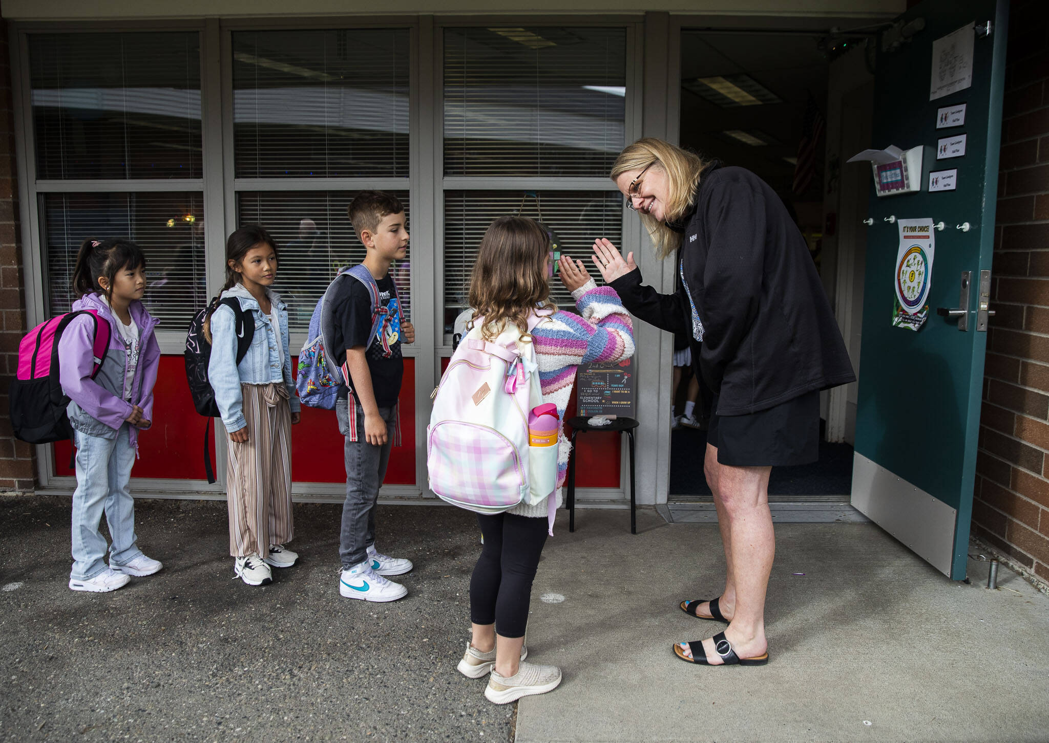 Second-grade teacher Debbie Lindgren high-fives her students as they line up outside the classroom on the first day of school at Hazelwood Elementary on Sept. 4, in Lynnwood. (Olivia Vanni / The Herald file photo)