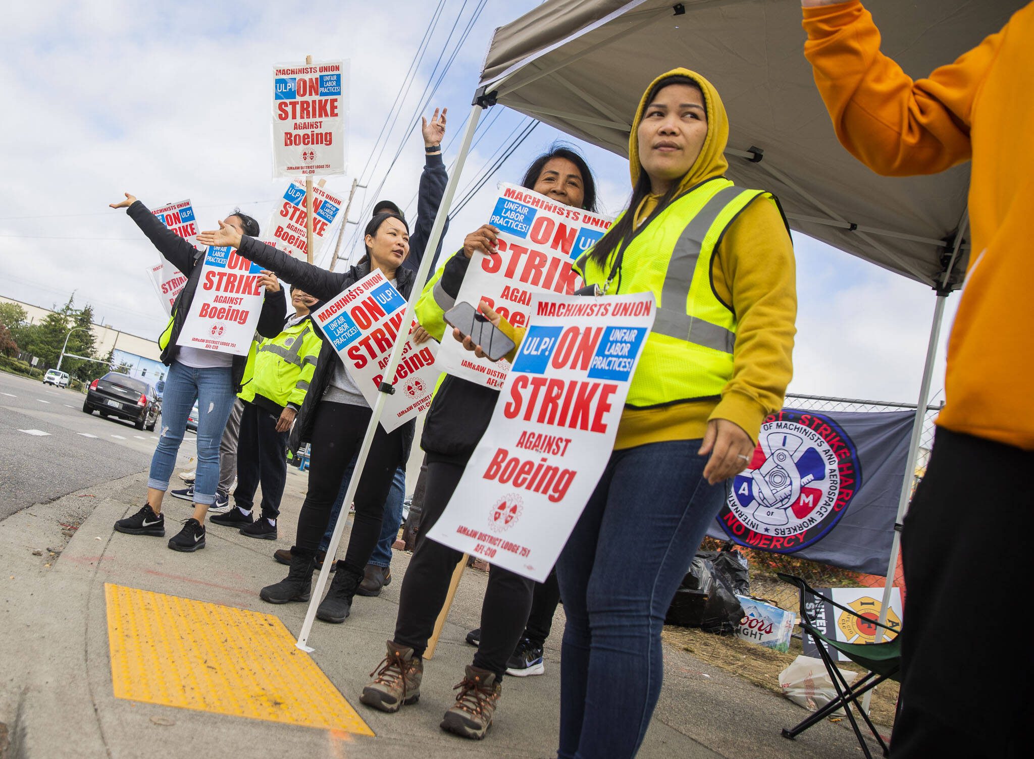 Nory Hang, right, watches cars pass by while picketing with fellow Boeing workers on strike along Airport Road on Sept. 16 in Everett. (Olivia Vanni / The Herald)