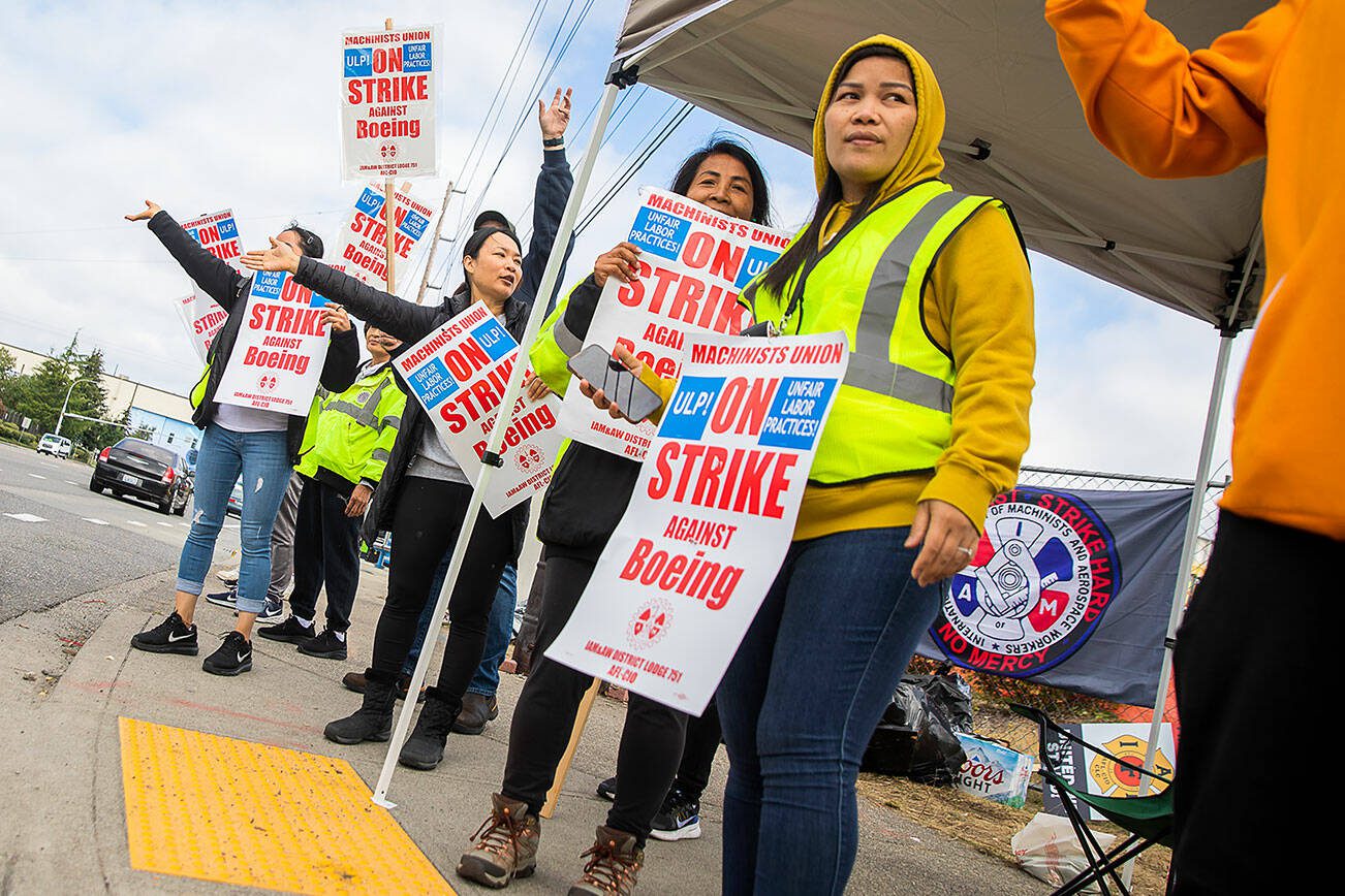 Nory Hang, right, watches cars pass by while picketing with fellow Boeing workers on strike along Airport Road on Sept. 16 in Everett. (Olivia Vanni / The Herald)