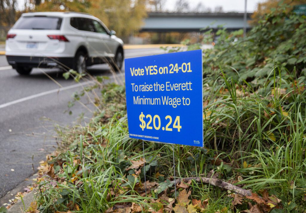 Cars getting onto an I-5 on-ramp drive past a sign encouraging people to vote “YES on 24-01” to raise the Everett minimum wage on Tuesday, Oct. 29, 2024 in Everett, Washington. (Olivia Vanni / The Herald)
