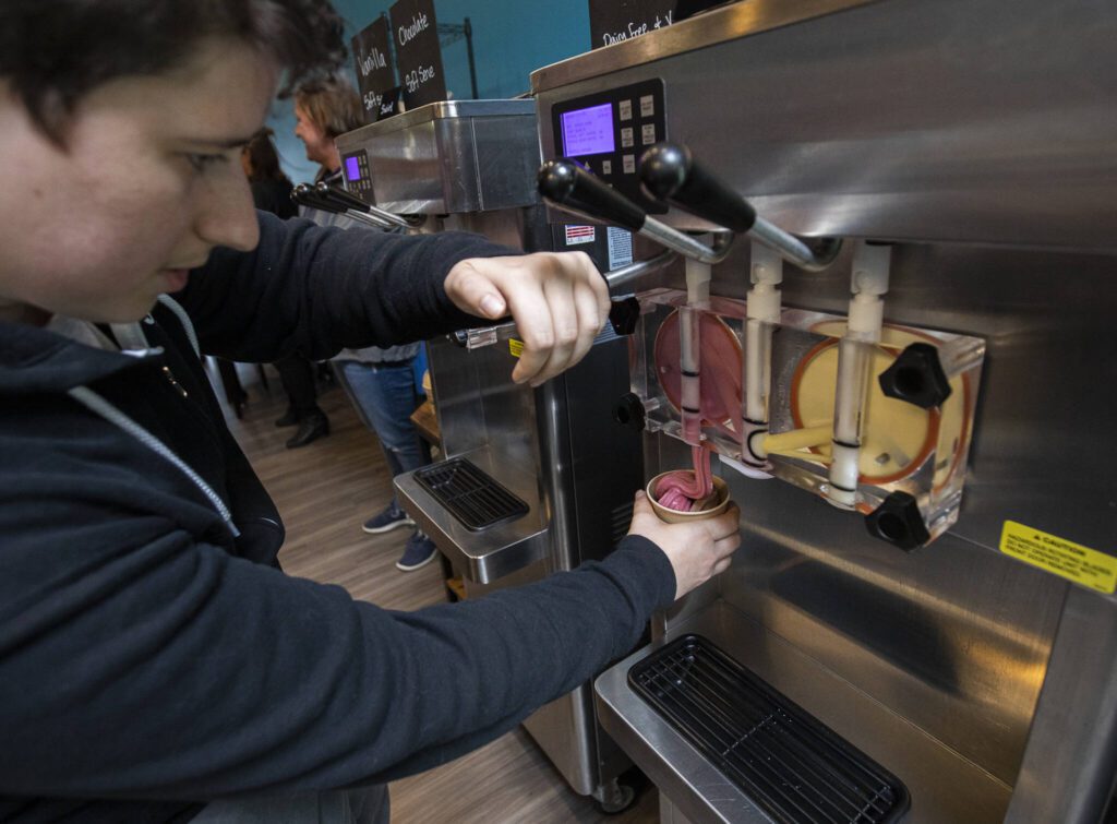 Rebekah Donyes fills up a cup with soft serve at the grand opening of The Ice Cream Bar on Friday, Oct. 18, 2024 in Everett, Washington. (Olivia Vanni / The Herald)
