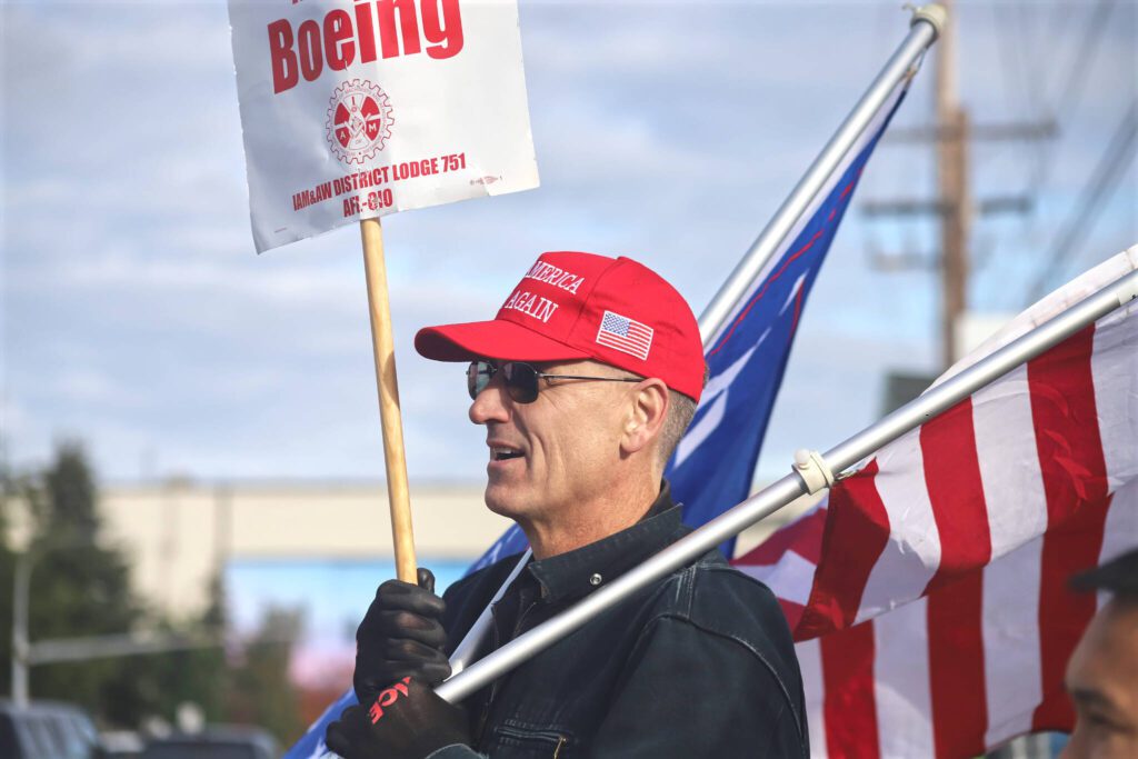 Bill Studerus, a Boeing Machinist for 39 years, holds a Boeing strike sign, an American flag and a campaign flag for former President Donald Trump while picketing at the Boeing plant on Thursday, Oct. 24, 2024, in Everett, Washington. (Michael Henneke / The Herald)
