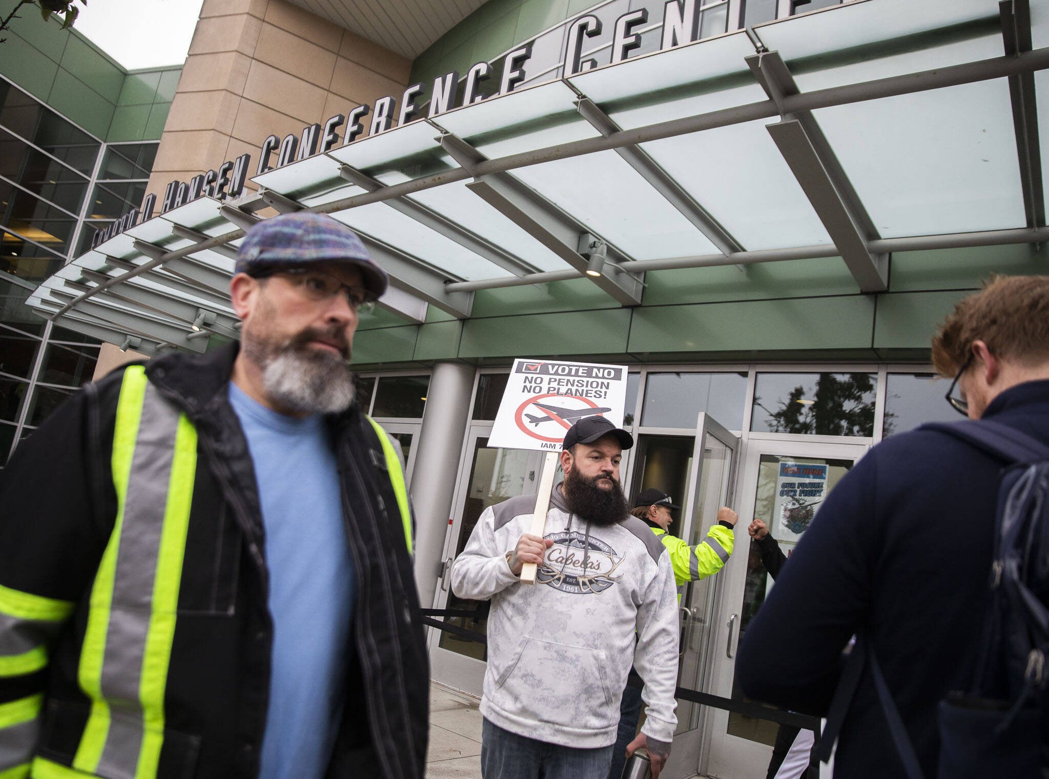 Matt Farnum, center, a machine repair mechanic at Boeing for 14 years, stands outside of Angel of the Winds Arena holding a “vote no” sign as people file inside to vote on the proposed contract on Wednesday in Everett. (Olivia Vanni / The Herald)