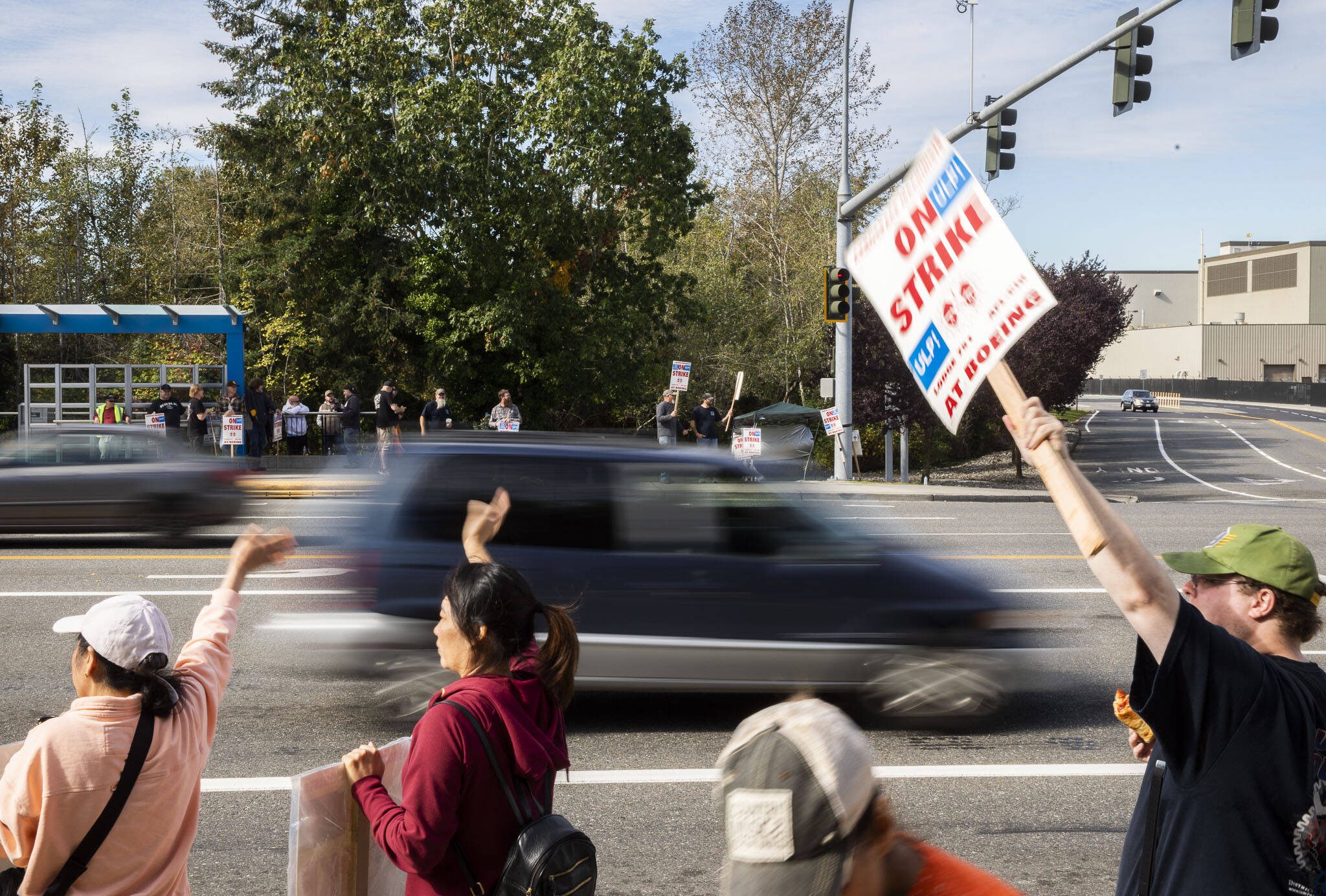 Cars drive past Boeing workers waving signs while picketing along Airport Road on Oct. 1 in Everett. (Olivia Vanni / The Herald)
