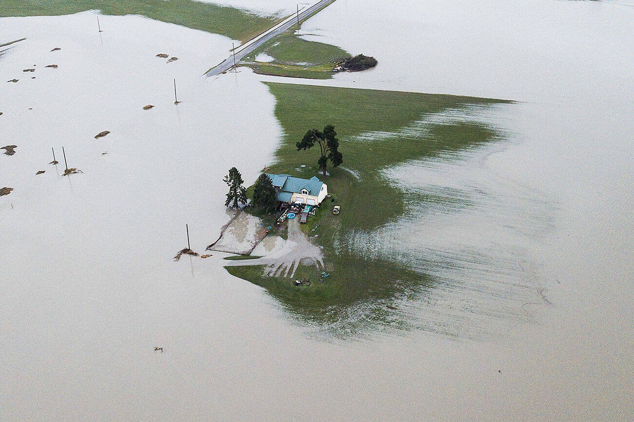 A house is completely surrounded by floodwater along Pioneer Highway on Wednesday, Dec. 6, 2023 in Stanwood, Washington. (Olivia Vanni / The Herald)