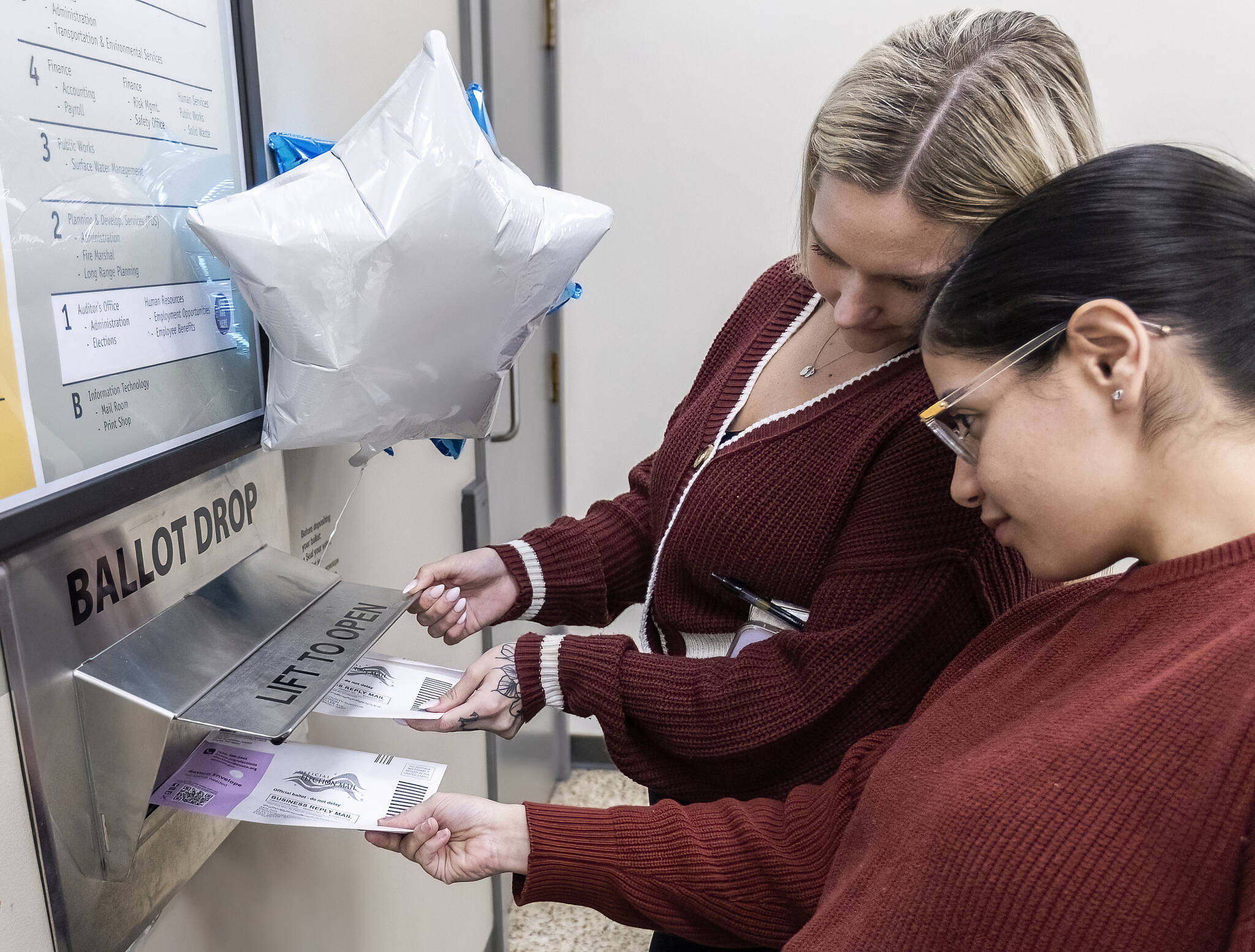 Payton Pavon-Garrido, 23, left, and Laura Castaneda, 28, right, push ballots into the drop box next to the Snohomish County Auditor’s Office on Tuesday, Nov. 5, 2024 in Everett, Washington. (Olivia Vanni / The Herald)