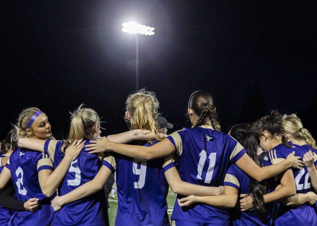 Lake Stevens players put their arms around each other in the huddle before the 4A state playoff game against Richland on Wednesday, Nov. 13, 2024 in Lake Stevens, Washington. (Olivia Vanni / The Herald)

