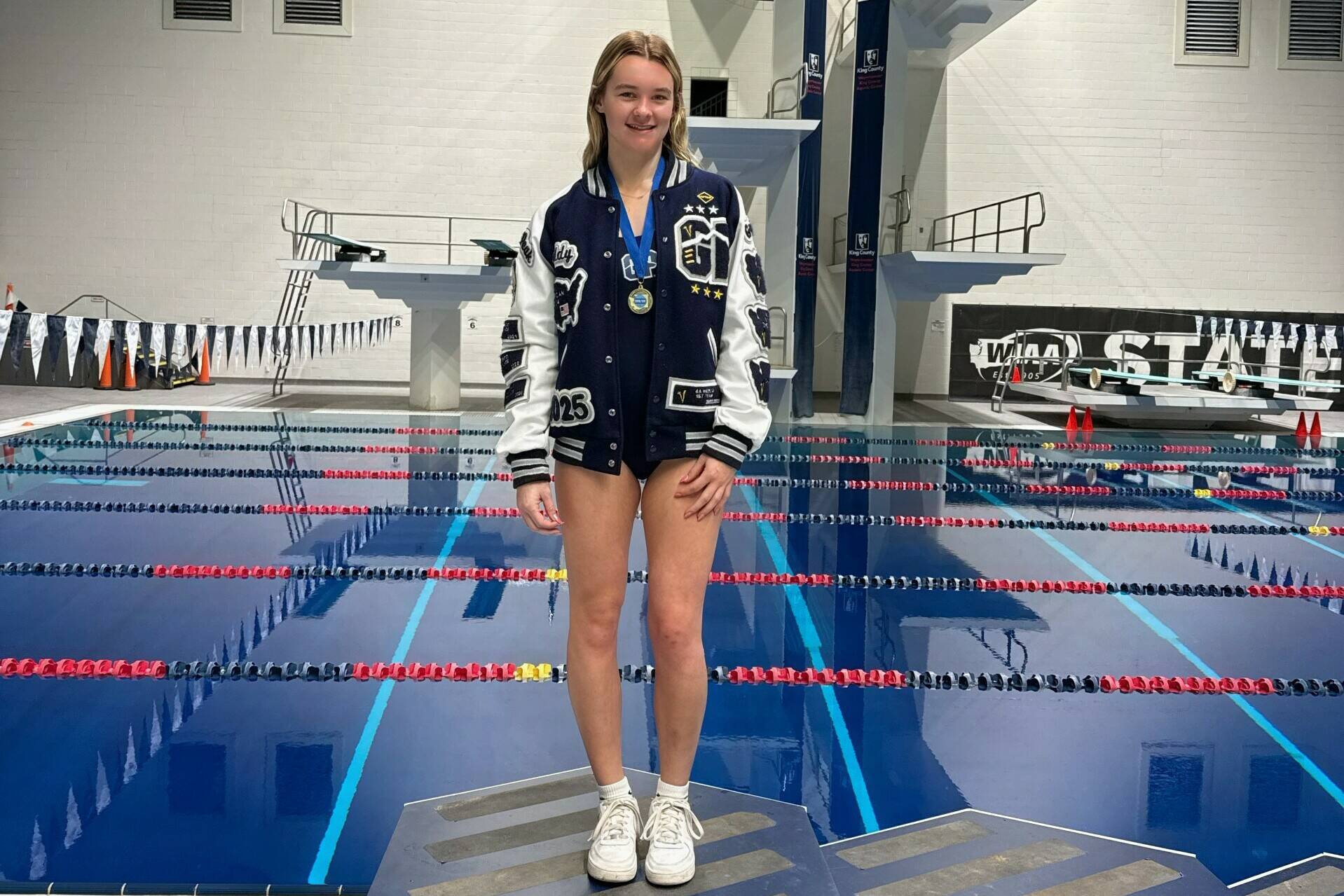 Glacier Peak High School diver Addison Farman stands on the championship platform after winning her second straight Class 4A 1-meter diving title at the King Country Aquatics Center on Thursday, Nov. 14, 2024. (Photo courtesy of Jamie Farman)