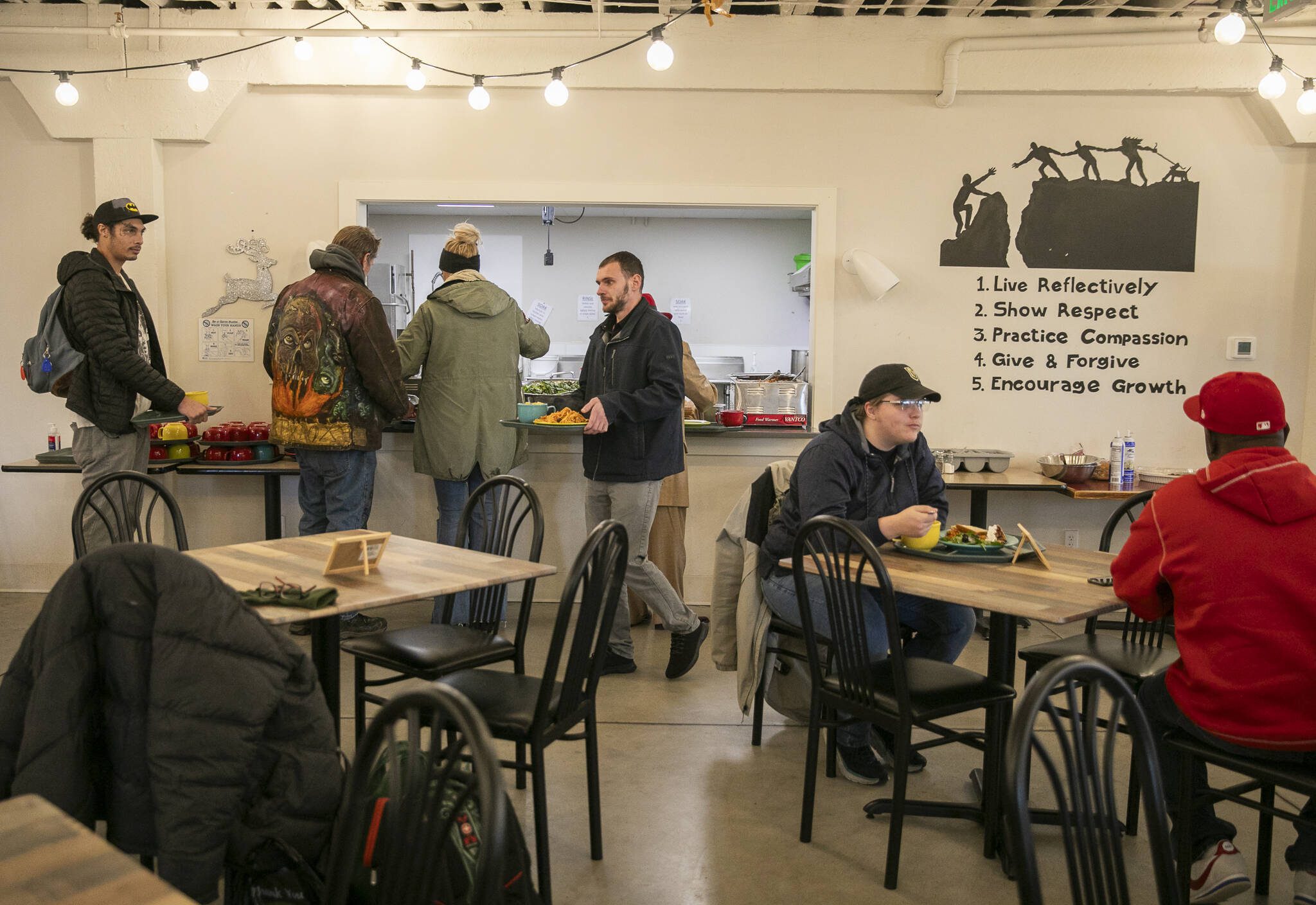 People line up to grab food at the Everett Recovery Cafe on Wednesday, Dec. 4, 2024 in Everett, Washington. (Olivia Vanni / The Herald)