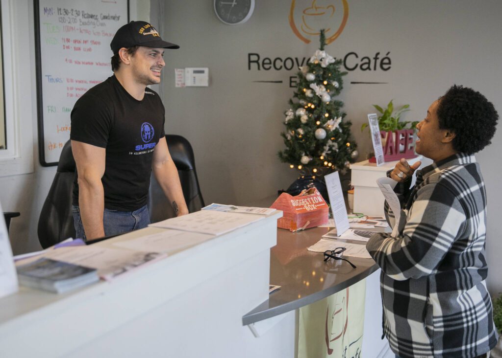 Recovery Cafe employees Daniel Seat, left, and April Echauri, right, run through questions someone might ask the front desk on Wednesday, Dec. 4, 2024 in Everett, Washington. (Olivia Vanni / The Herald)
