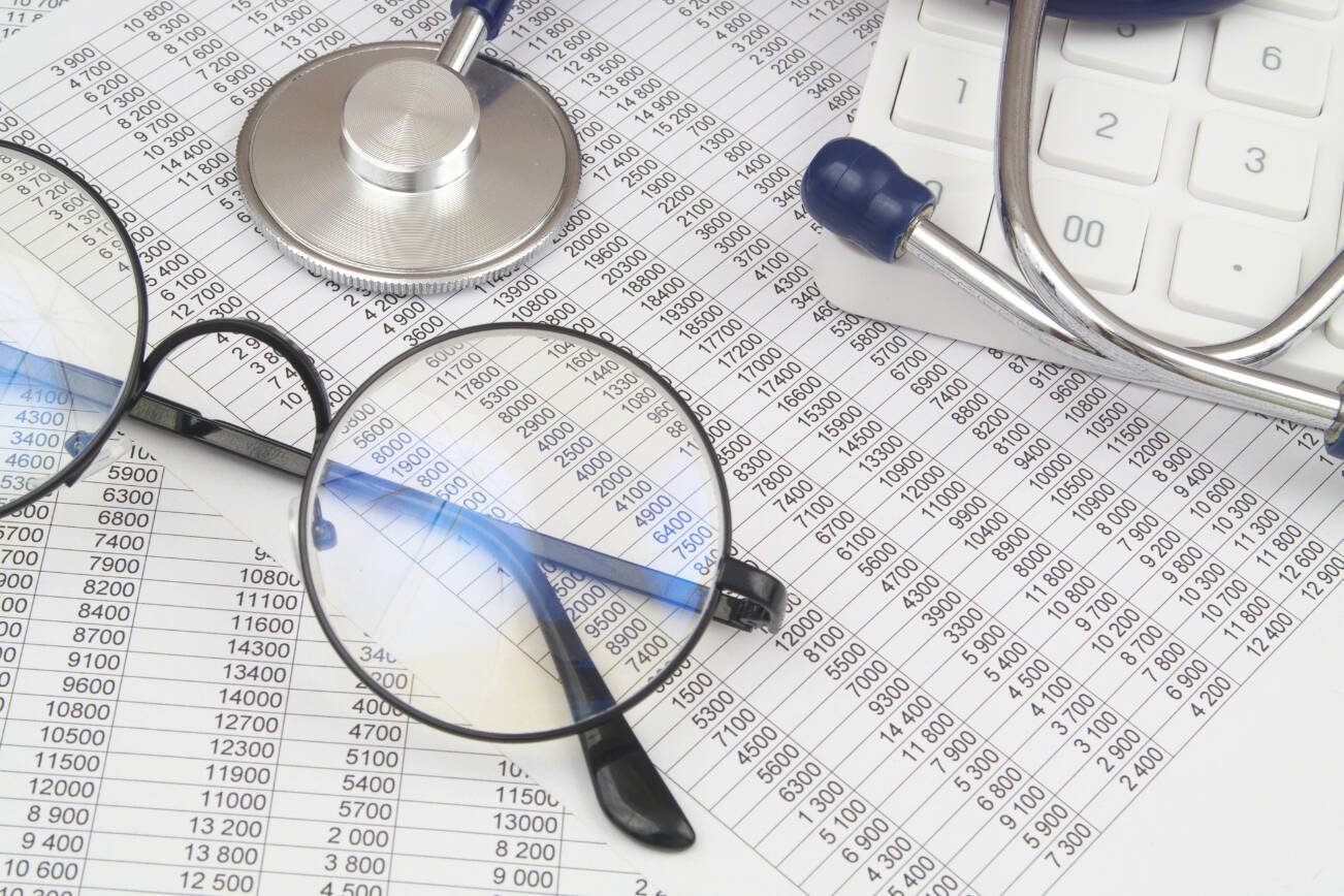 Stethoscope, glasses and calculator on financial documents close up.