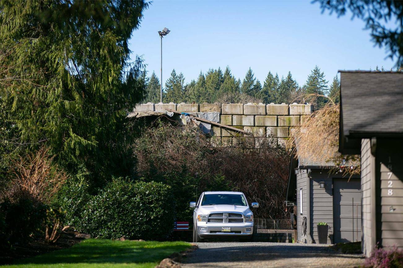 A cement block wall holds back refuse at United Recycling and Containers behind a home on Tuesday, March 5, 2024, in Snohomish, Washington. Years ago, the homes on 109th Ave SE overlooked a 150-foot drop into an old gravel pit. (Ryan Berry / The Herald)