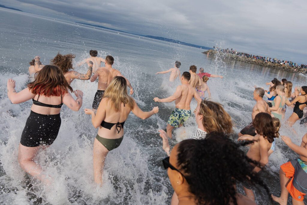 People rush into the cold water of the Edmonds shoreline on Wednesday, Jan. 1, in Edmonds, Washington. (Will Geschke / The Herald)
