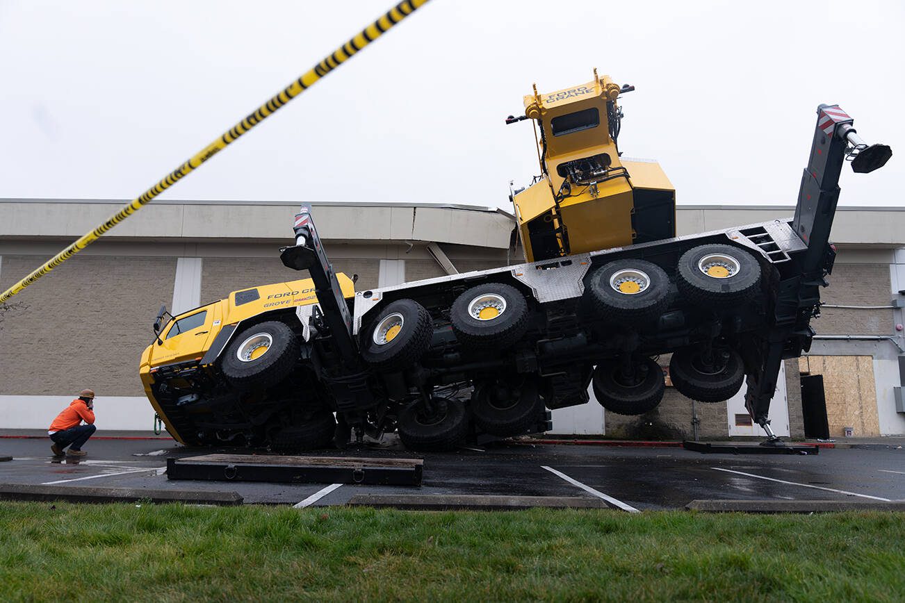 A construction worker looks at a crane which crashed into a section of the Everett Mall on Thursday, Jan. 16, 2025 in Everett, Washington. (Will Geschke / The Herald)