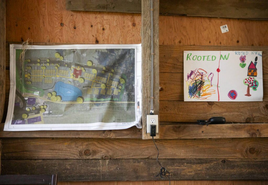 A map of Rooted Northwest’s housing clusters hangs on the wall next to a hand drawn art piece on Thursday, Jan. 23, 2025 in Arlington, Washington. (Olivia Vanni / The Herald)
