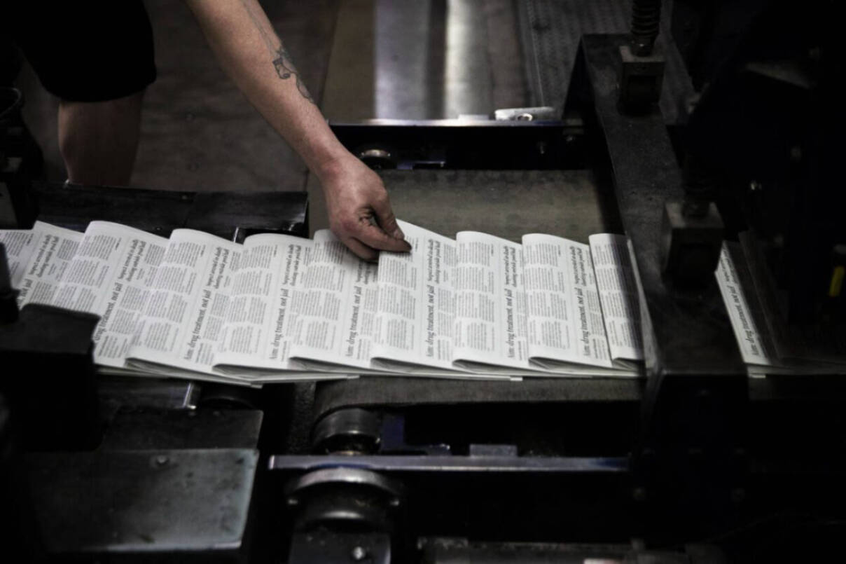 A press operator grabs a Herald newspaper to check as papers roll off the press in March 2022 in Everett. (Olivia Vanni / The Herald file photo)