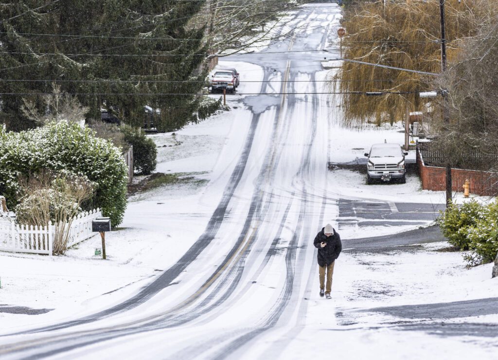 Kenneth Hawkes navigates snow and ice while he walks up a hill along 224th Street on Monday, Feb. 3, 2025 in Edmonds, Washington. (Olivia Vanni / The Herald)
