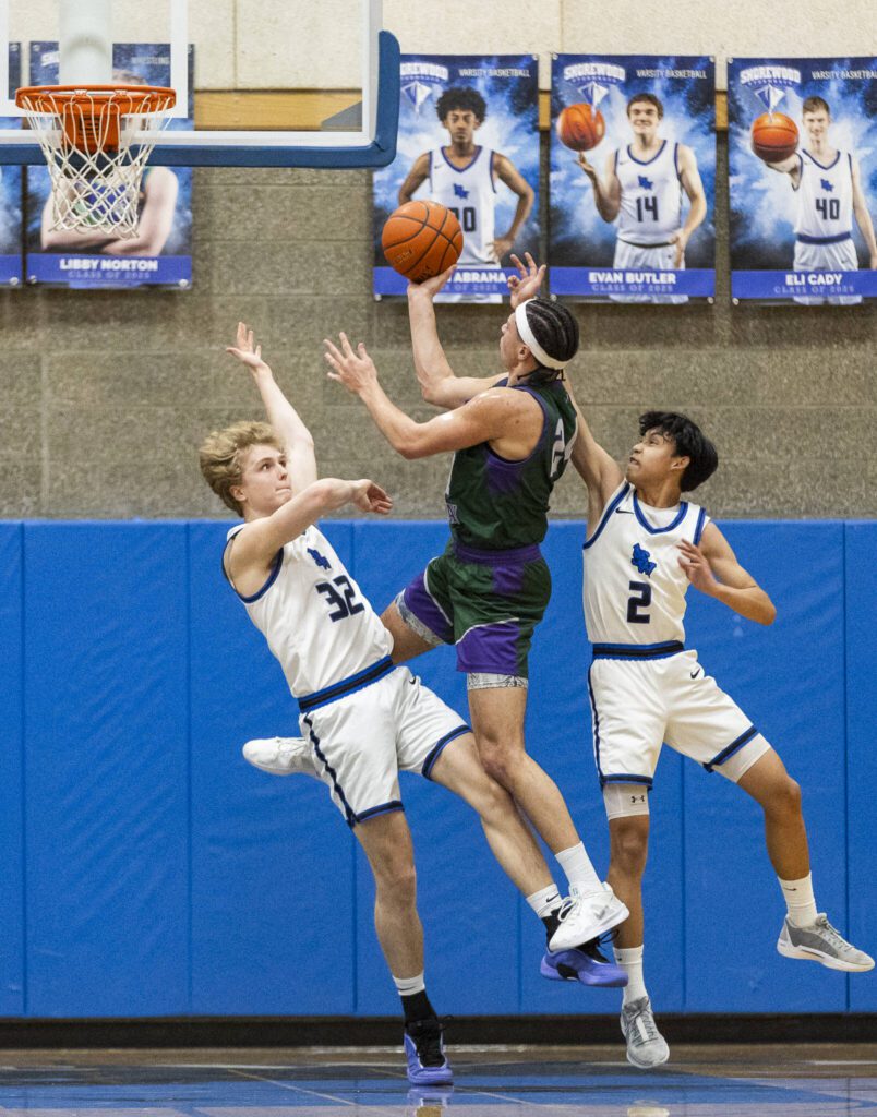 Shorewood’s Elijah Haub and Kevin Cambronero try to block the layup attempt by Edmonds-Woodway’s Julian Gray during the game on Tuesday, Feb. 4, 2025 in Shoreline, Washington. (Olivia Vanni / The Herald)
