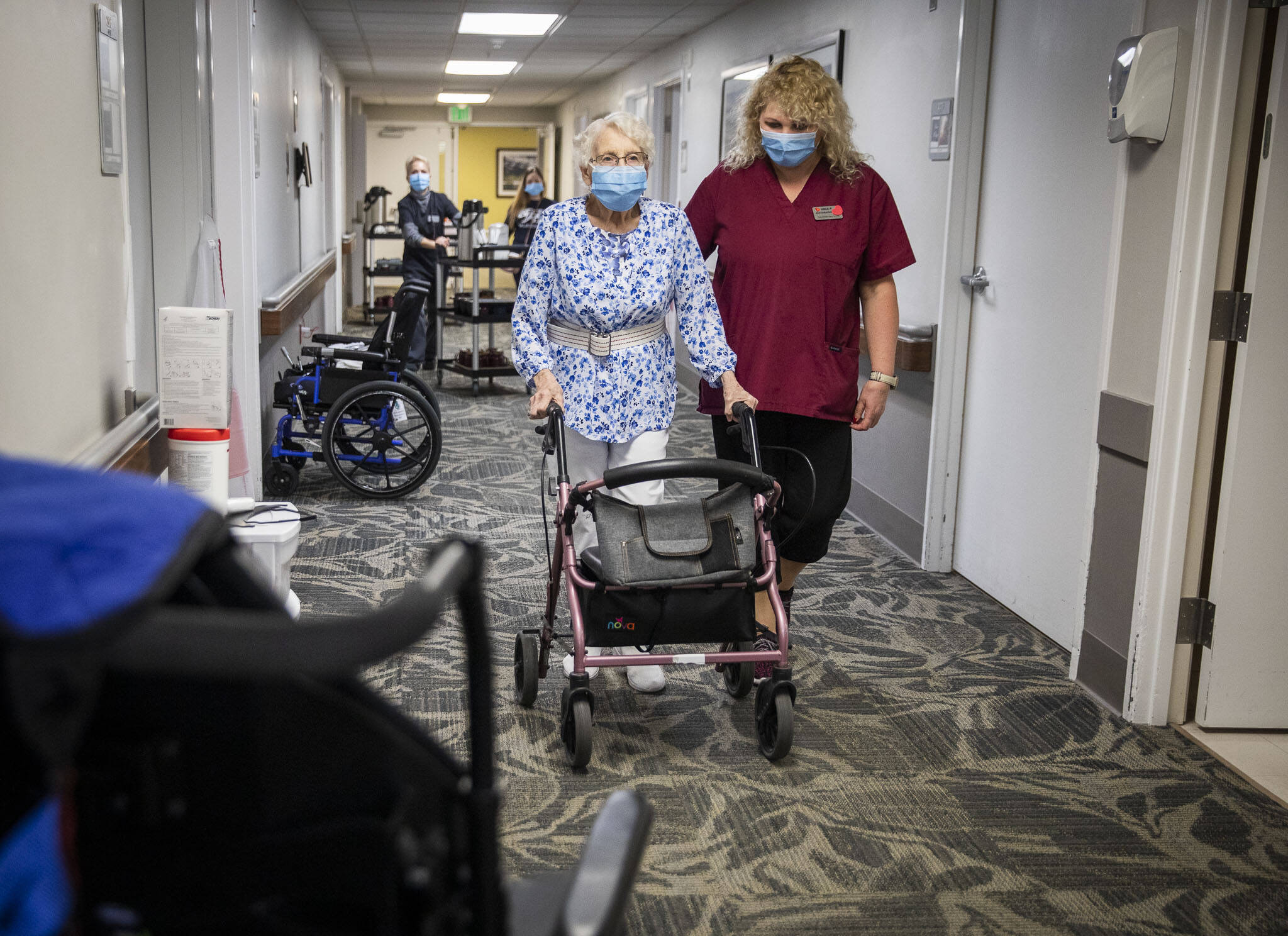 Certified Nursing Assitant Nina Prigodich (right) leads restorative exercises with long term care patient Betty Long, 86, at View Ridge Care Center on in February, 2023 in Everett. (Olivia Vanni / The Herald file photo)