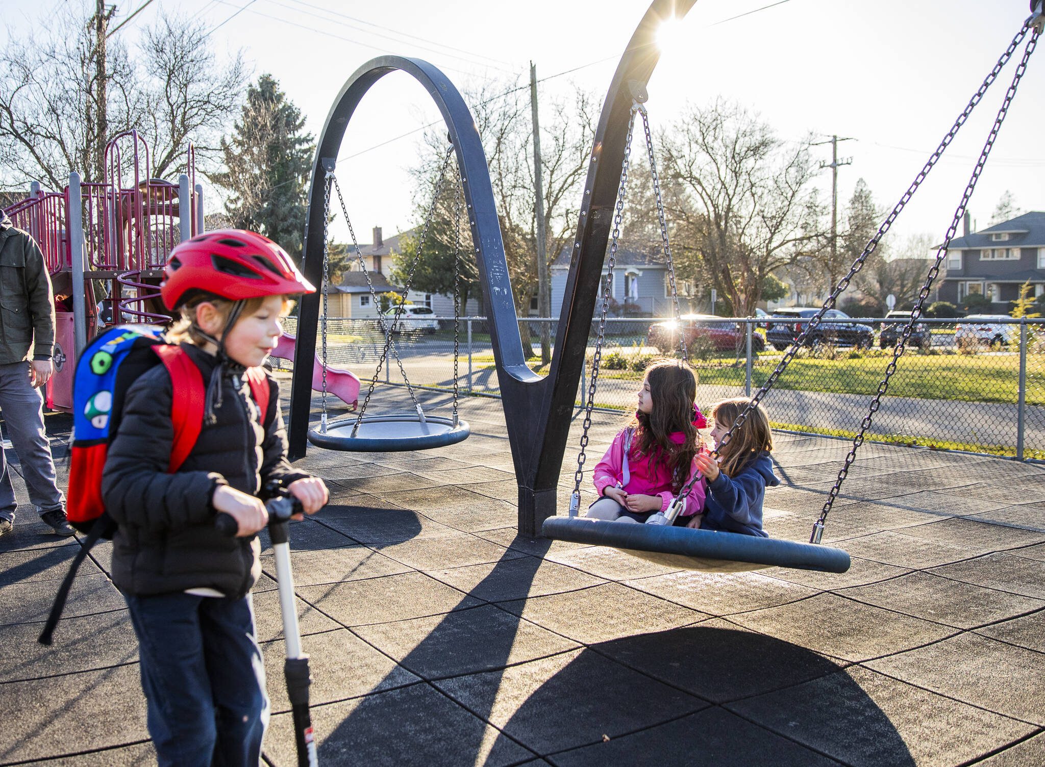 Alina Langbehn, 6, center, and Vera A., 6, right, sit on a swing together at Drew Nielsen Neighborhood Park after school on Tuesday, Jan. 28, 2025 in Everett, Washington. (Olivia Vanni / The Herald)