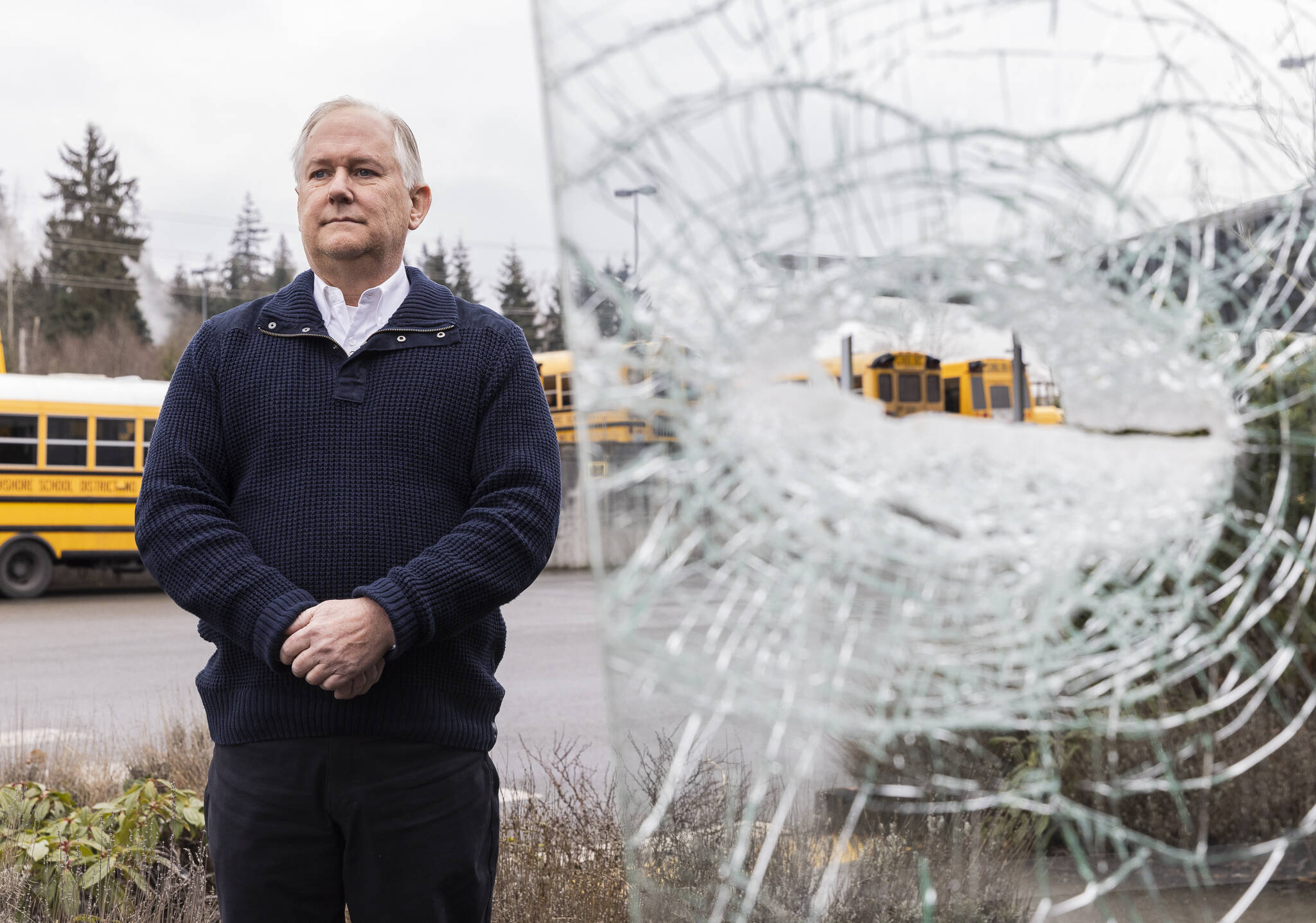 Northshore School District bus driver Stewart O’Leary pictured next to his bus’s shattered driver’s side windshield on Friday, Feb. 14, 2025 in Bothell, Washington. (Olivia Vanni / The Herald)