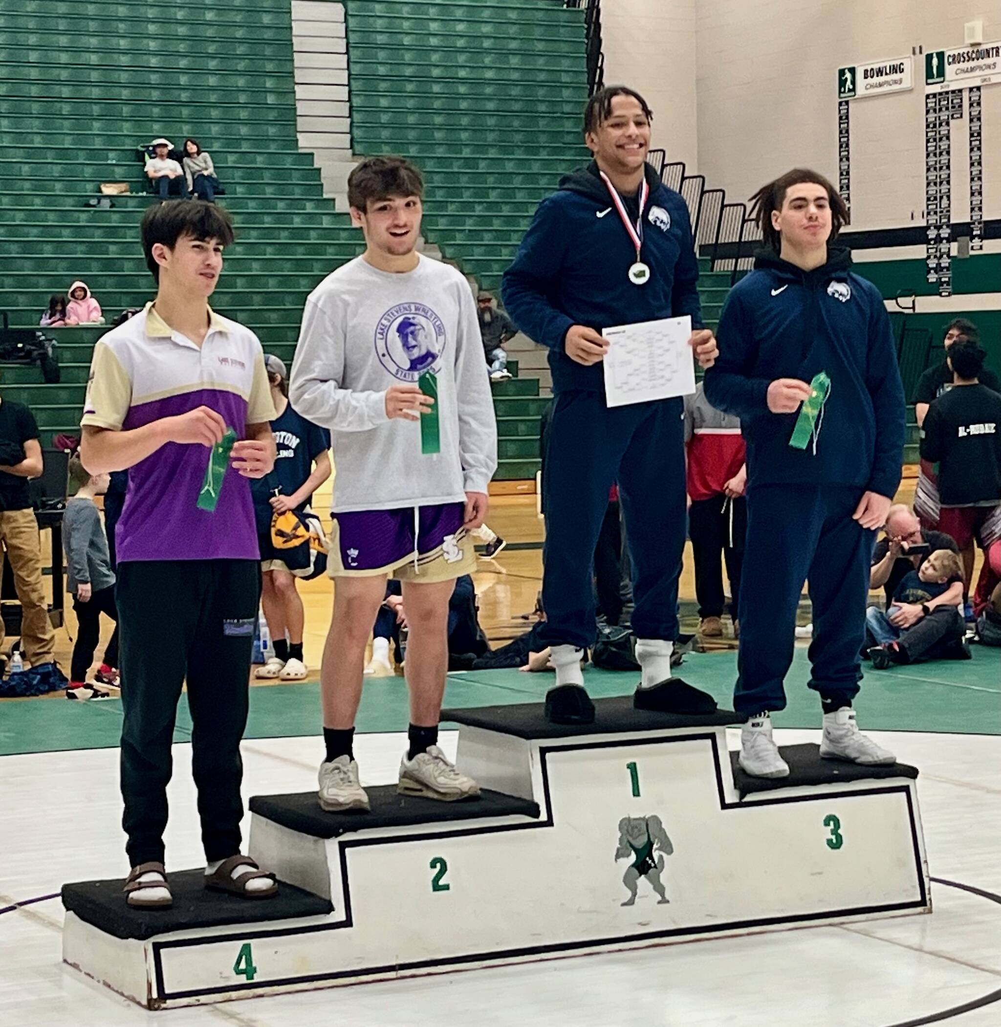 Arlington junior Tre Haines stands atop the podium after winning the District 1 Boys 4A Wrestling 157-pound championship on Feb. 8 in Mill Creek, Washington. Lake Stevens senior Jarrell David placed second, Arlington junior Marquell Butler placed third and Lake Stevens sophomore Felix Ramsey placed fourth in the weight class. (Joe Pohoryles / The Herald).