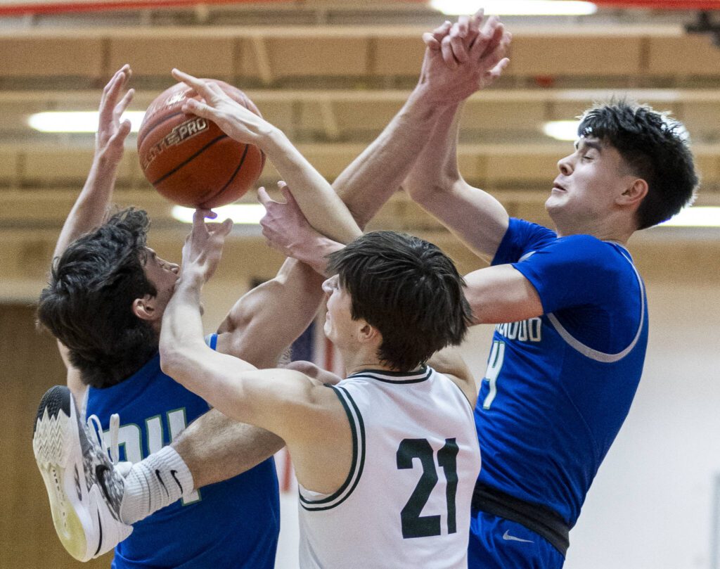 Edmonds-Woodway’s Luke Boland and Shorewood’s Jaden Marlow and Max Nguyen get tangled midair while reaching for a rebound during the 3A district semifinal game on Wednesday, Feb. 19, 2025 in Marysville, Washington. (Olivia Vanni / The Herald)
