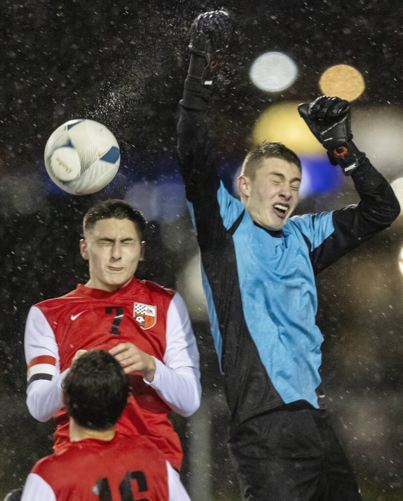 Water sprays off the ball as Snohomish’s Gabriel Cortes leaps to head the ball out of the box during the game against Glacier Peak on Wednesday, March 12, 2025 in Snohomish, Washington. (Olivia Vanni / The Herald)
